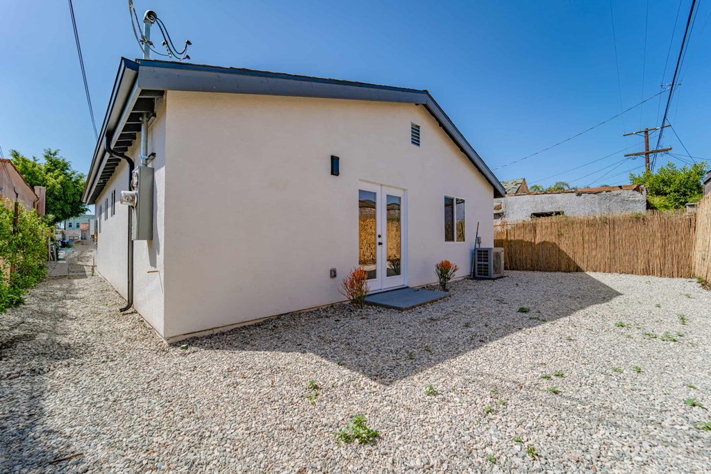 the front of a white house with a gravel yard