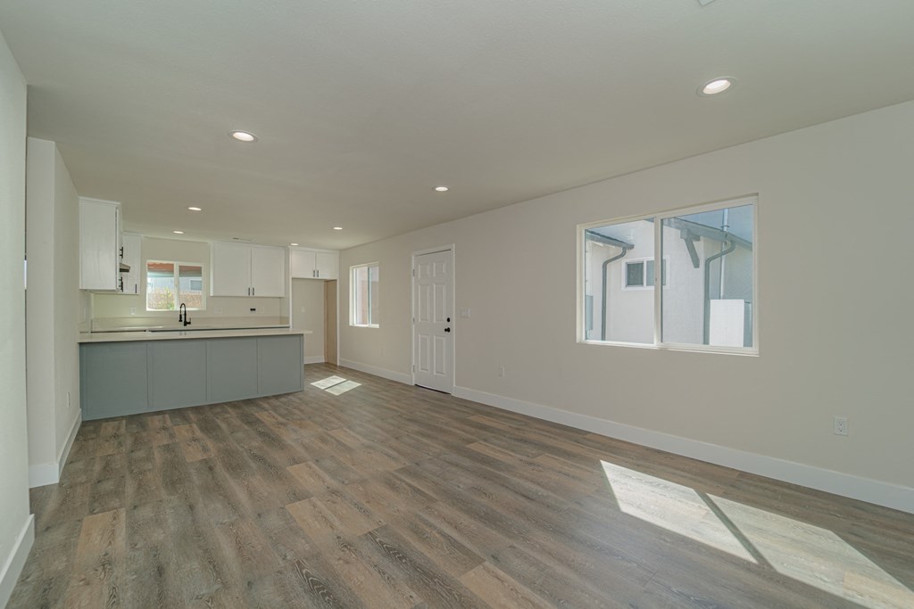 an empty living room and kitchen with wood flooring