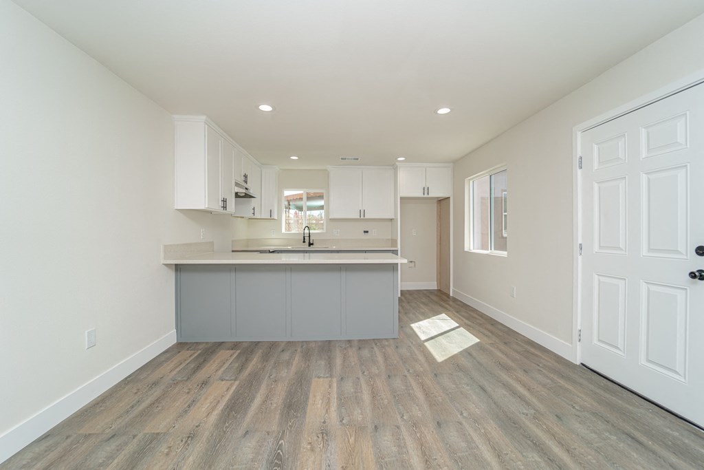 an empty kitchen with white cabinets and a gray counter top and a door