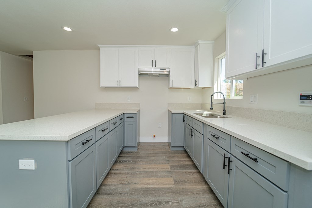 a large white kitchen with white counter tops and blue cabinets