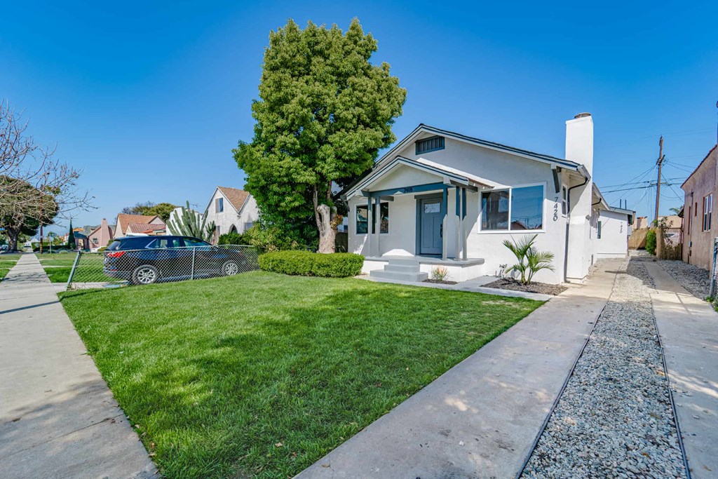 a white house with a lawn and a car parked in front of it
