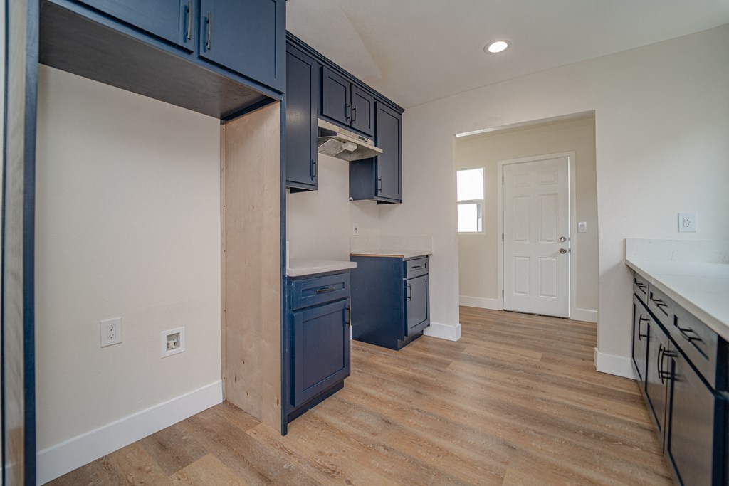 an empty kitchen with blue cabinets and a wood floor