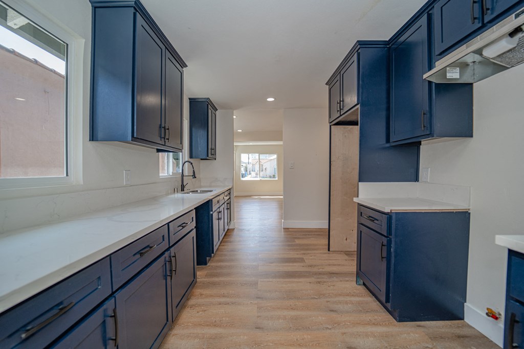 a large kitchen with blue cabinets and white counter tops