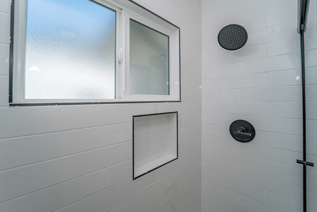 a shower with a window and a mirror in a bathroom