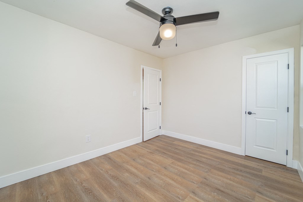 an empty room with white walls and a ceiling fan