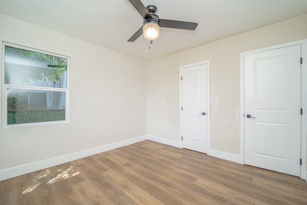 an empty bedroom with a ceiling fan and a window