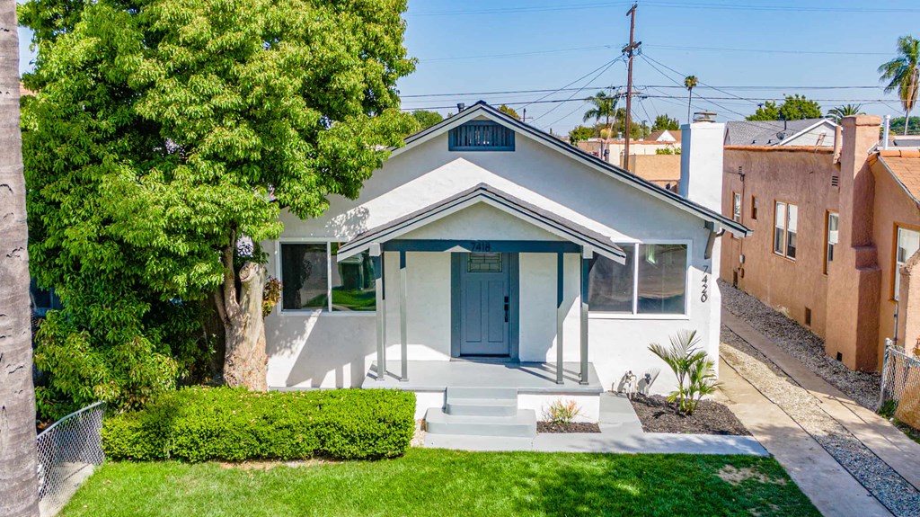 a small white house with a blue door and a tree