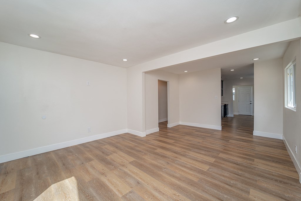 an empty living room with white walls and wood flooring