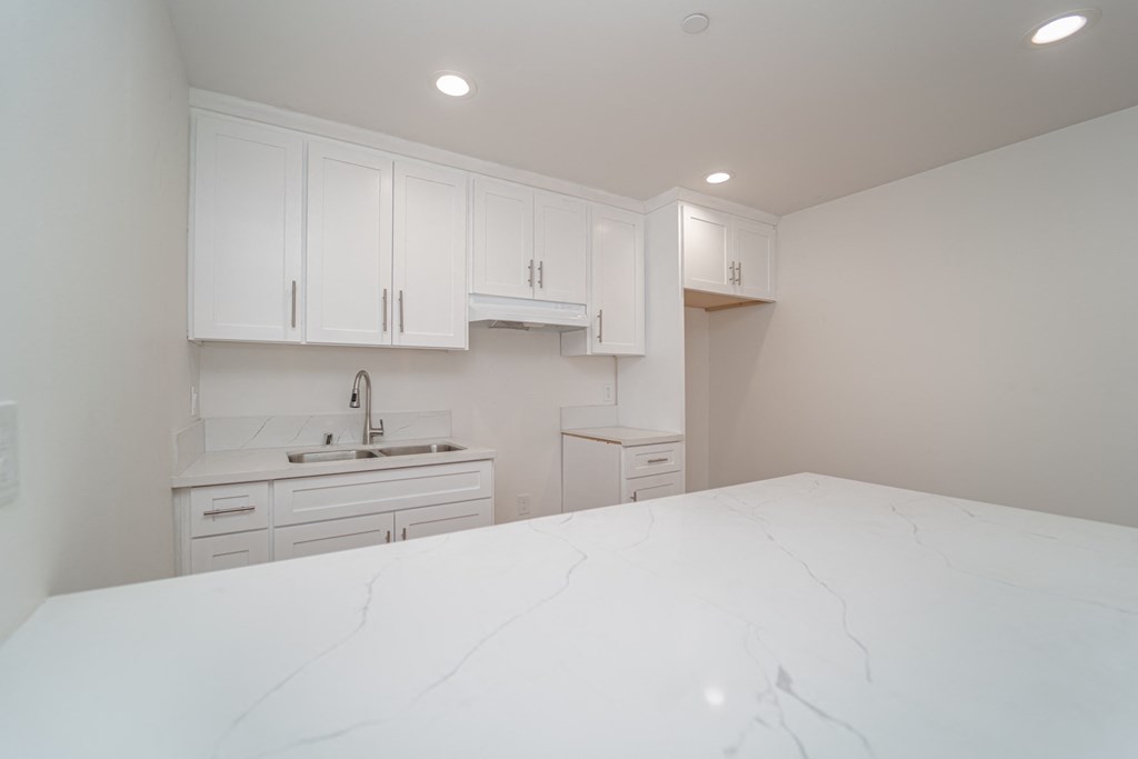 a kitchen with white cabinets and a marble counter top