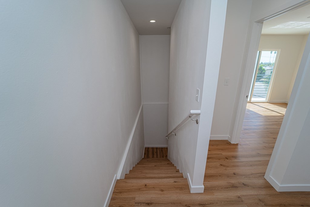an empty hallway with wood floors and white walls
