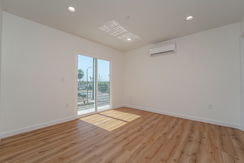 an empty living room with wood flooring and a door to a balcony