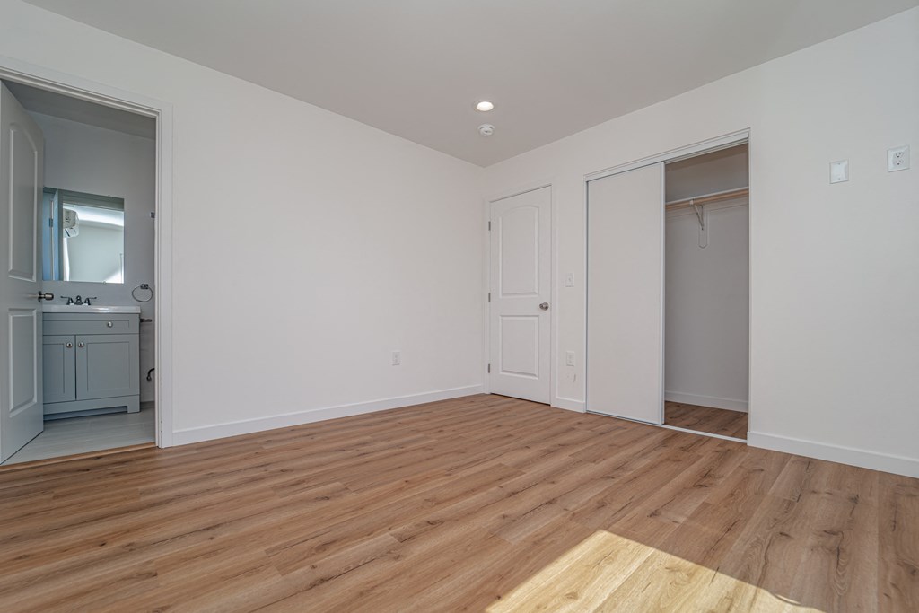 a living room with a hardwood floor and a door to a bathroom