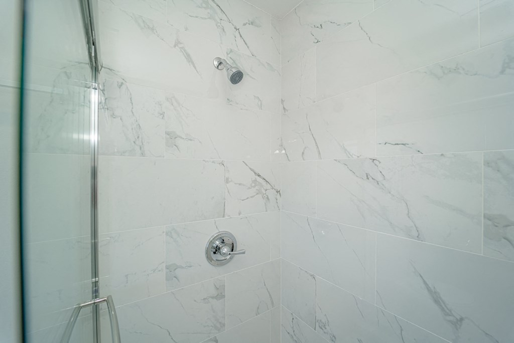 a white marble shower with a glass door