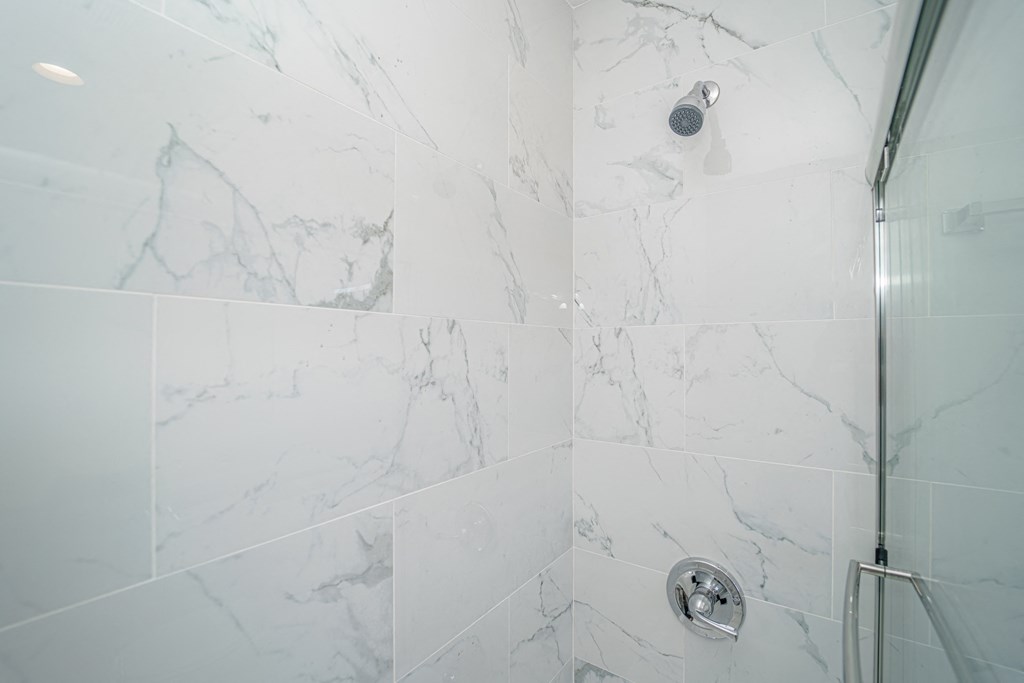 a shower with white marble tiles in a bathroom