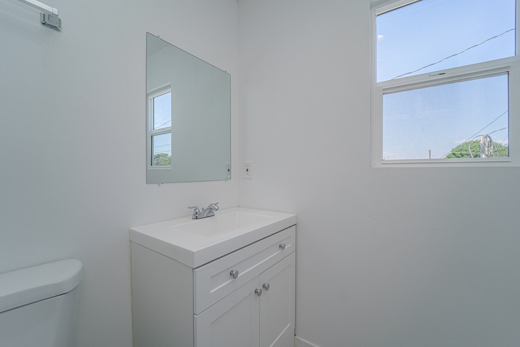 a bathroom with a sink and a mirror and a window