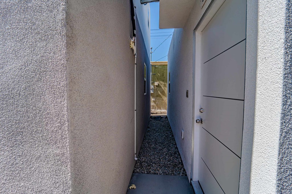 a narrow hallway with a white door leading to a house