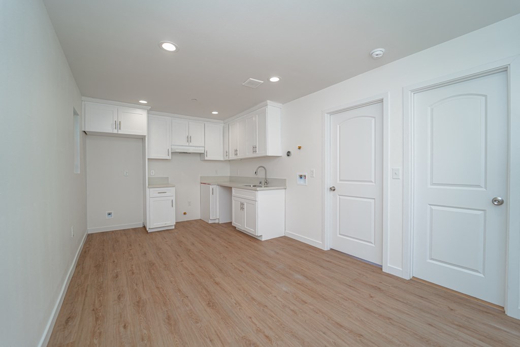 an empty kitchen with white cabinets and a wooden floor