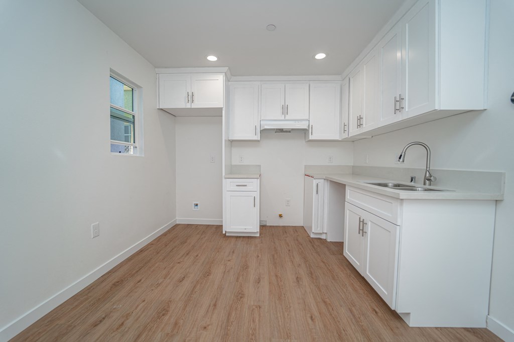 an empty kitchen with white cabinets and white counter tops