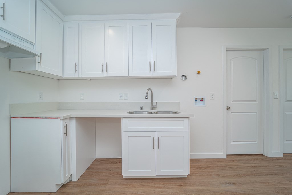 an empty kitchen with white cabinets and a sink
