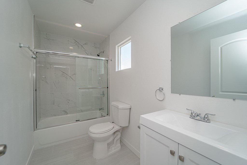 a white bathroom with a shower toilet and sink