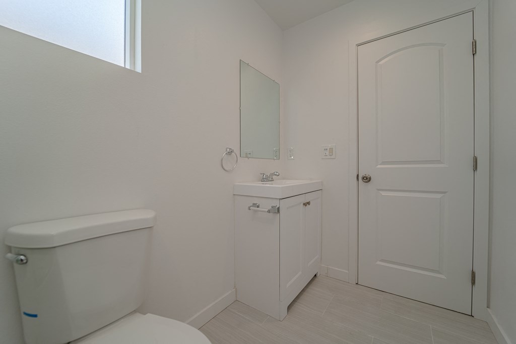 a white bathroom with a toilet sink and a window