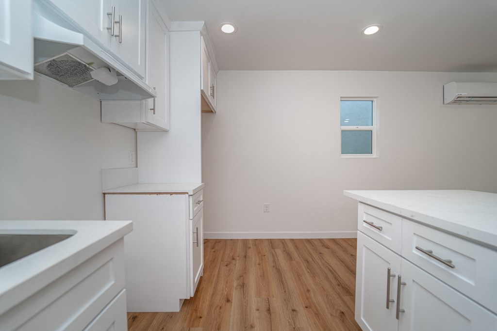 a kitchen with white cabinets and a hard wood floor