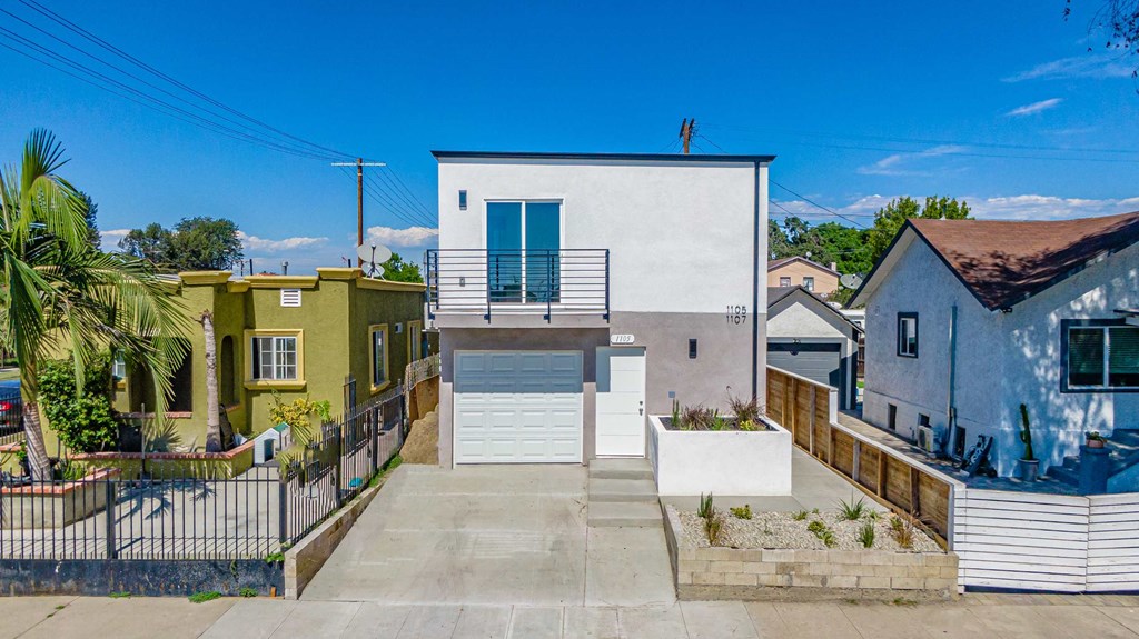 a white house with a garage next to some buildings