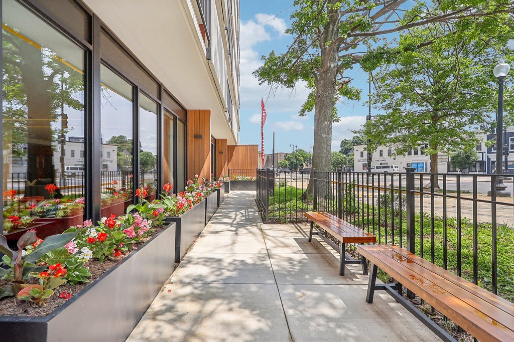 an outside patio with benches and flowers and a building with a flag