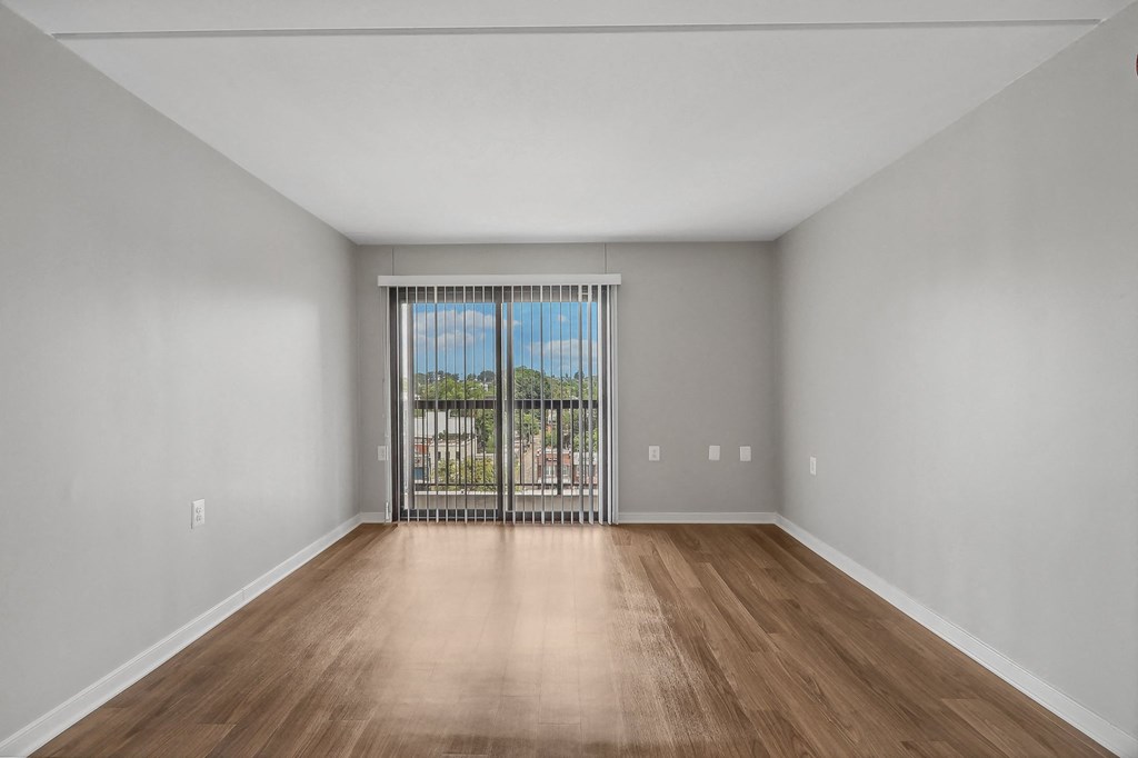 an empty living room with a large window and wooden floors