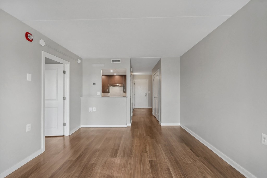 the living room and dining room of an apartment with wood floors and white walls