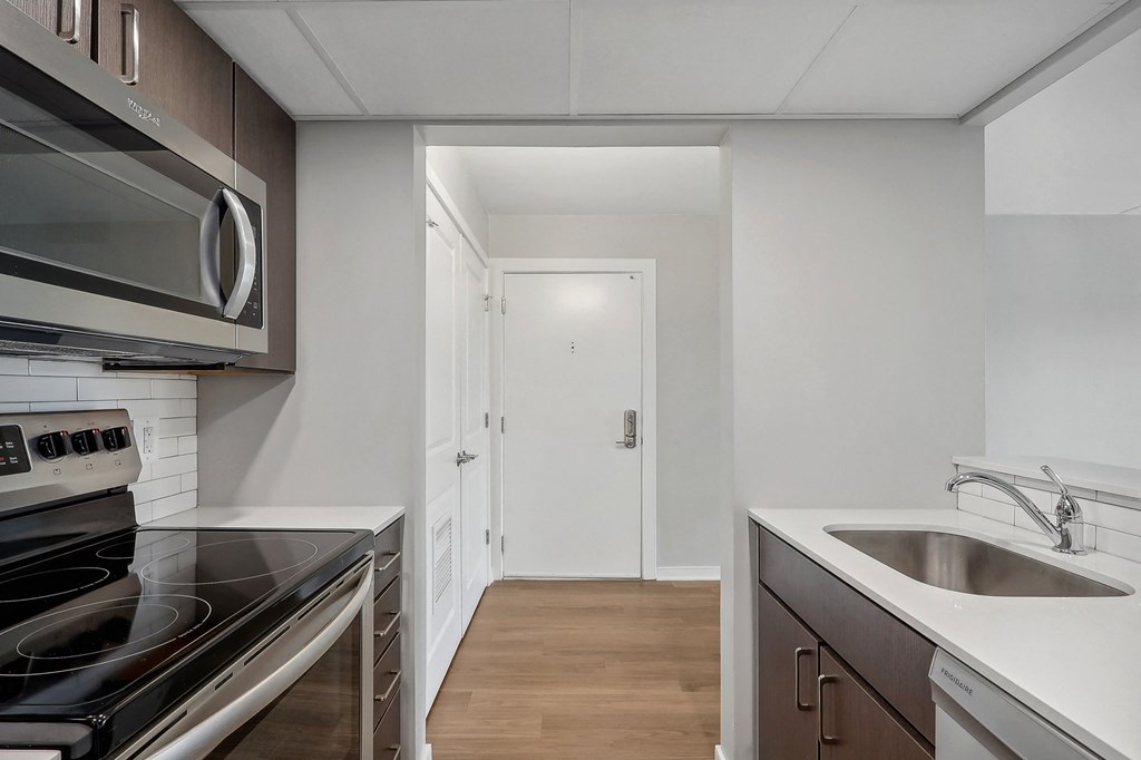 a kitchen with a sink and a stove and a door to a hallway
