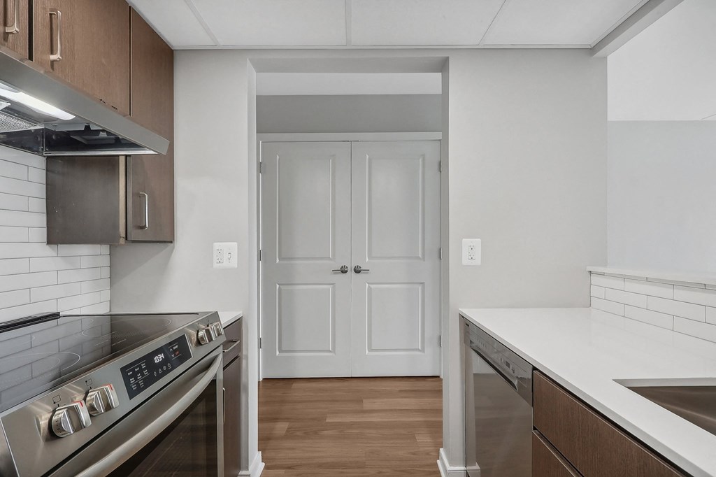 an empty kitchen with stainless steel appliances and a door to a hallway