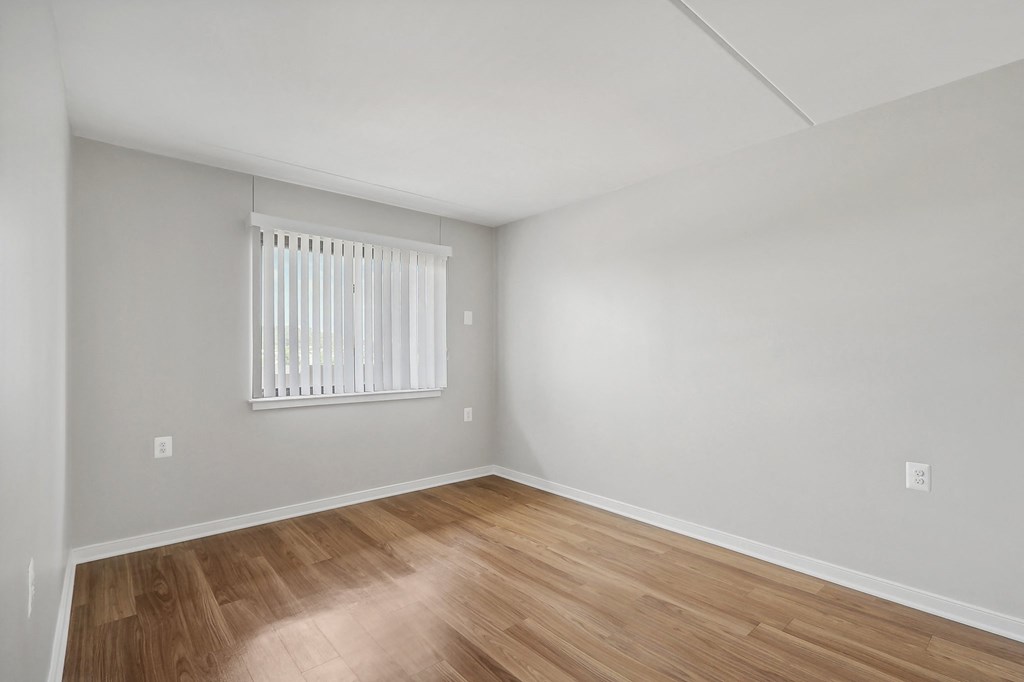 the living room of an apartment with wood flooring and a window
