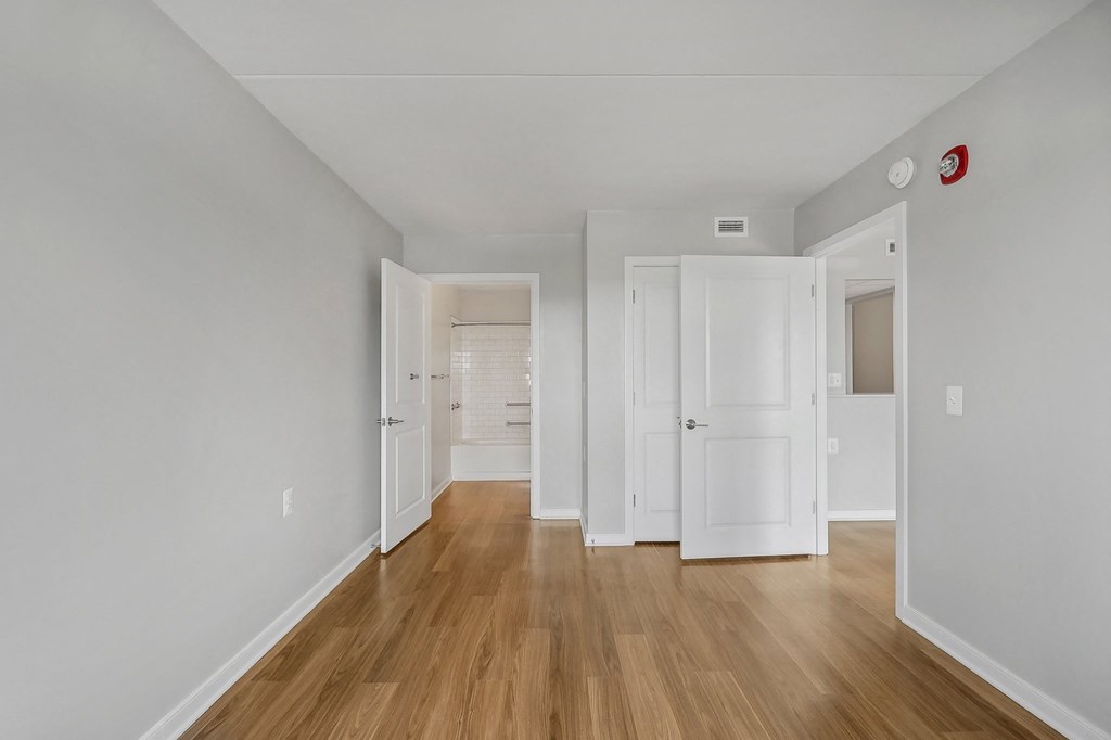 a living room with white walls and wooden floors and white closets