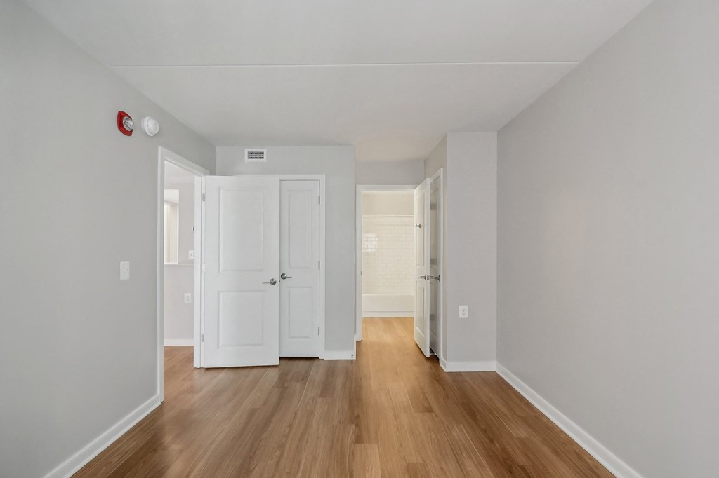 the living room of an apartment with wood floors and white walls
