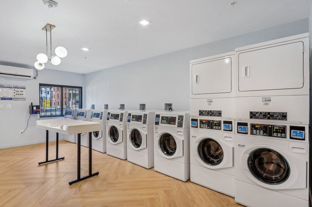 a laundry room with a row of washers and dryers and a table with