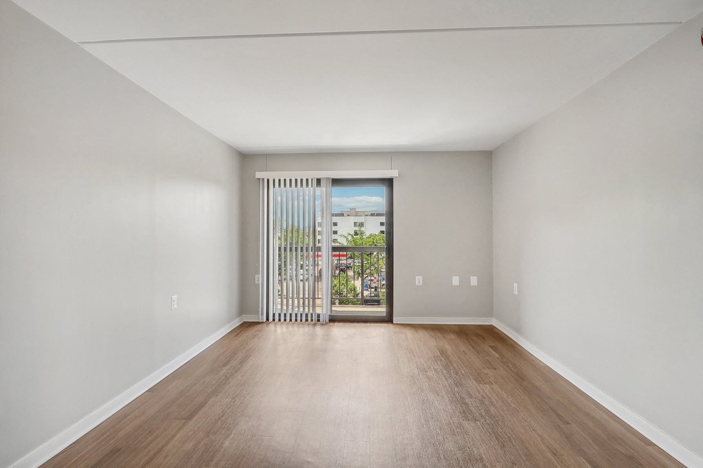 an empty living room with wood flooring and a door to a balcony