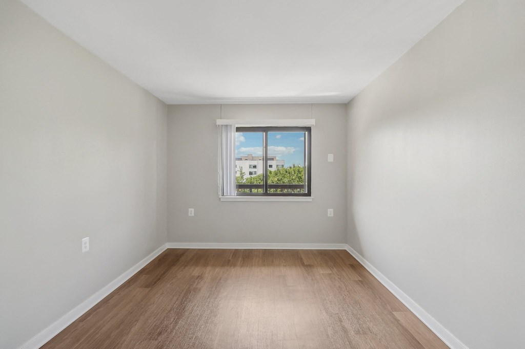 an empty room with wood floors and a window