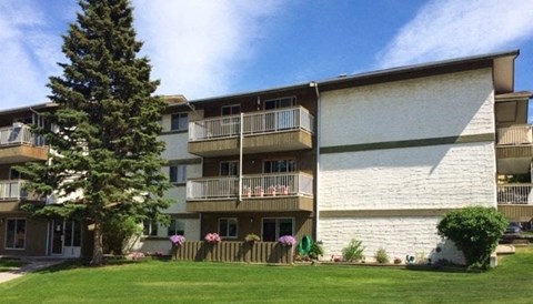 A large apartment complex with a green lawn in front.