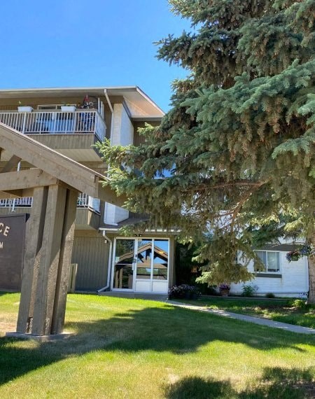 A large white house with a balcony and a tree in front.