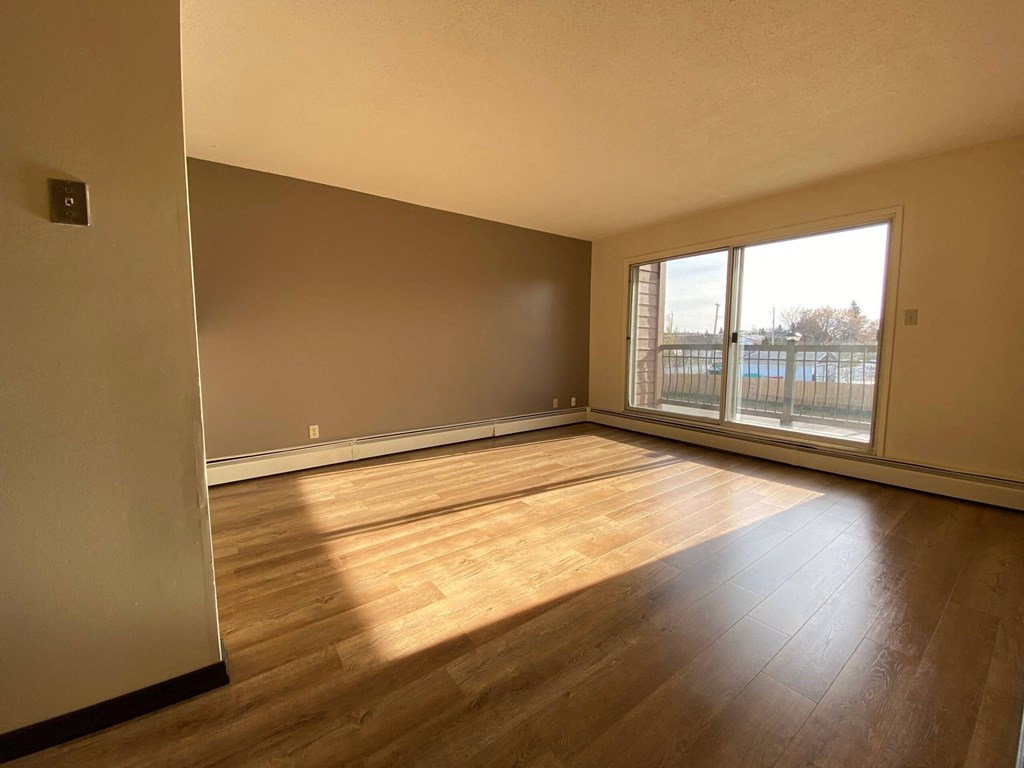 an empty living room with wood floors and a window