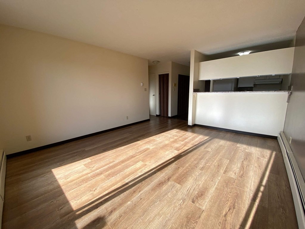 an empty living room with wood floors and a white wall
