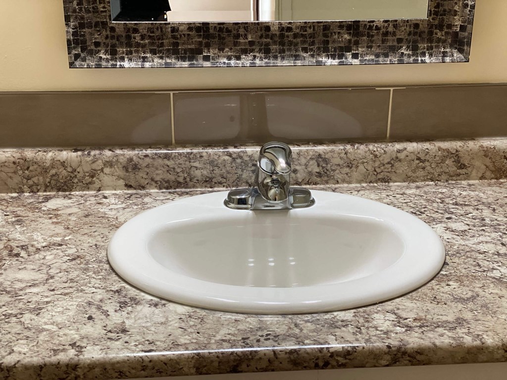 a sink in a granite counter top with a mirror above it