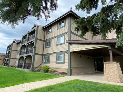 the exterior of a apartment building with a sidewalk and grass