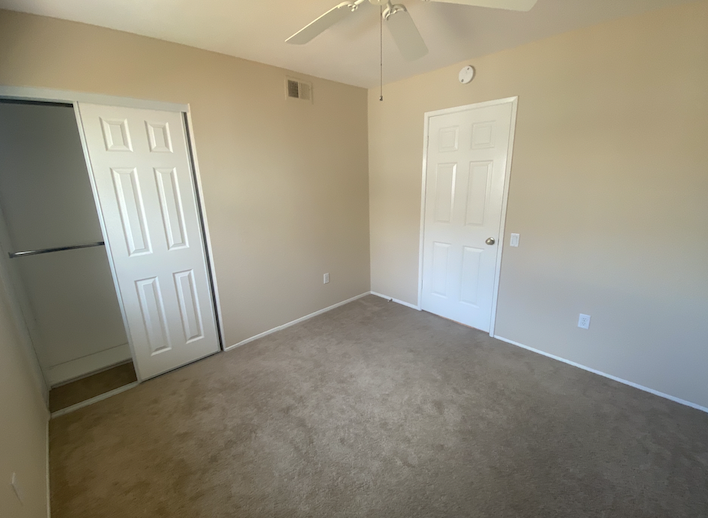an empty room with two doors and a refrigerator