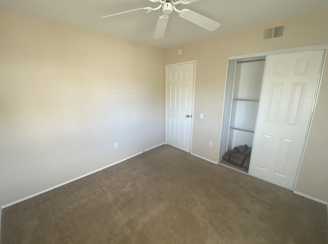 an empty room with a ceiling fan and a closet