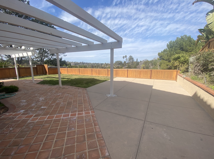 a patio with a white canopy over it and a brick sidewalk