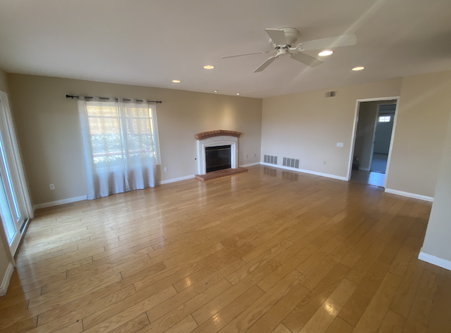 an empty living room with wood floors and a fireplace