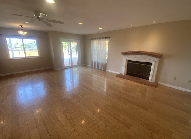 an empty living room with a fireplace and wooden floors