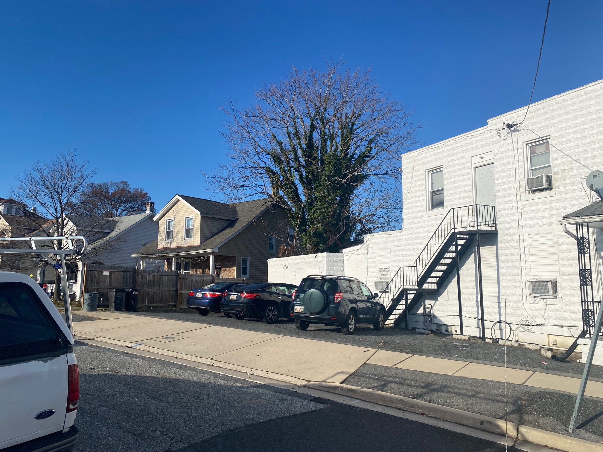 a city street with cars parked in front of a white house